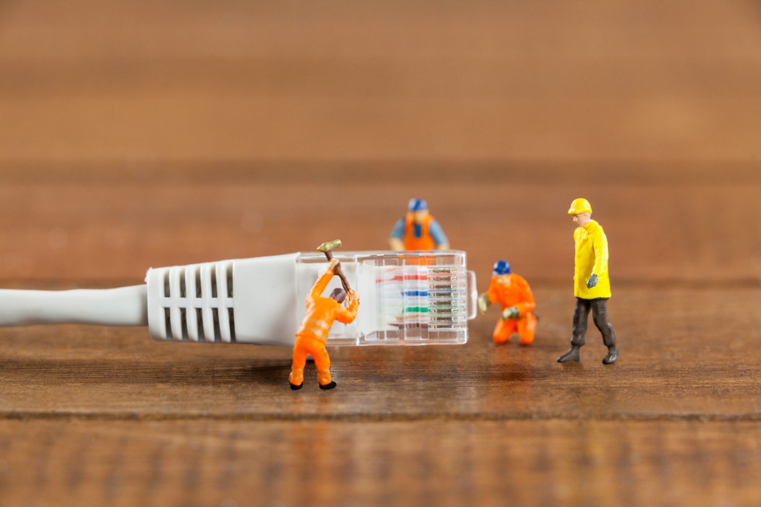 Miniature engineer and workers working with lan cable Miniature engineer and workers working with lan cable on wooden table